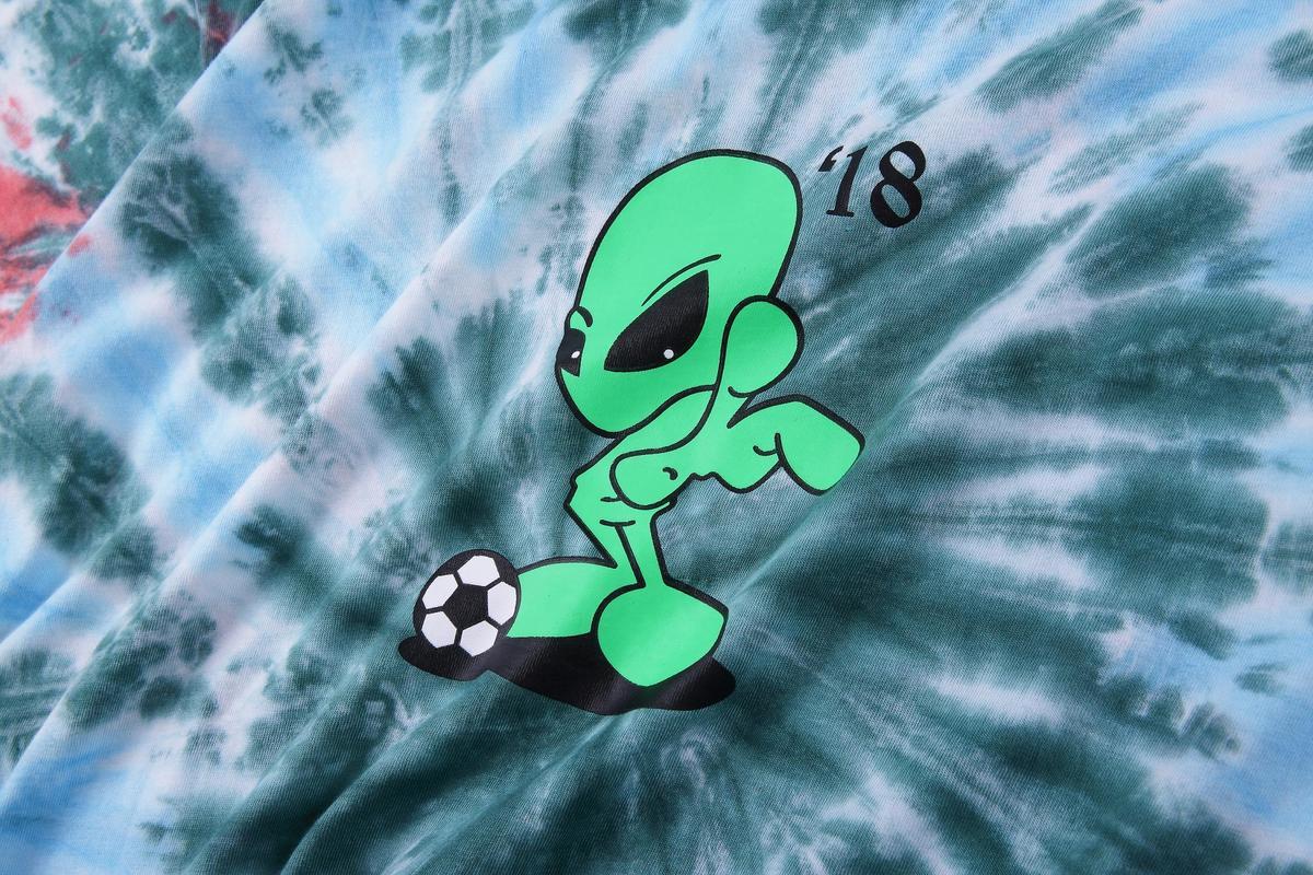 A vibrant tie-dye t-shirt with a graphic of an alien playing football.